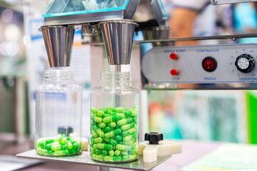 close up transparent plastic bottle under nozzle dispenser component of automatic medicine capsule...