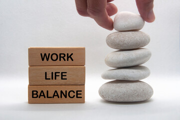 Work life balance text on wooden blocks with hand stacking zen stones. New ways of working concept.