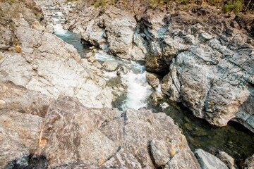 Narrow rocky river flowing downstream on a sunny day