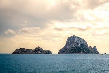 Es Vedra rocky island at sunset with a cloudy sky in the background