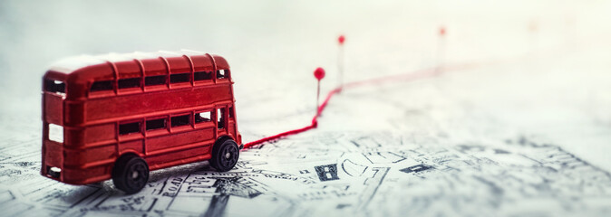 Red bus, pins and route laid on a map of the city. Concept on the  adventure, discovery,...