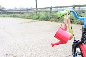 red watering can and the kid's garden tools hanging on the bike 