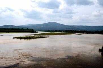 View of the lake with dark green hills in the background.