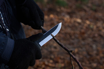 Schnitzen eines Astes mit einem Messer im Wald
