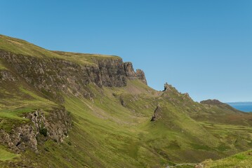 View of the scenic Quiraing hills in Scotland with the beautiful clear blue sky in the background