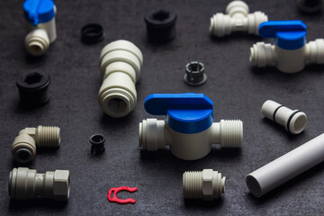 Detail of plastic plumbing, air product, pipe and tools. Valves, elbow and tee with locking clip on black background. Fitting industry
