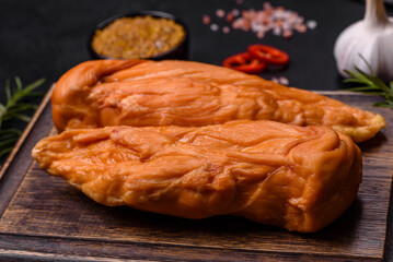 Tasty smoked fillet of chicken breast with spices and herbs on a wooden cutting board