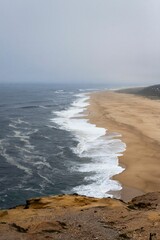 Vertical shot of the ocean waves washing the sandy beach