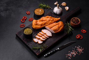 Tasty smoked fillet of chicken breast with spices and herbs on a wooden cutting board