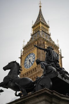 Low angle shot of bronze statue of Boadicea near iconic clock tower Big Ben in Westminster, London.