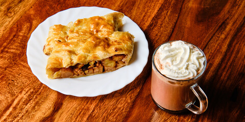 Apple strudel with cocoa drink on table