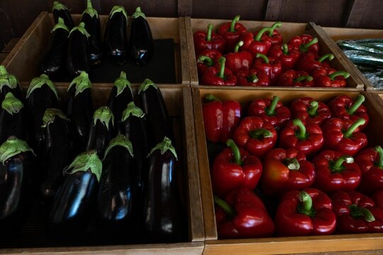 Red bell peppers and Eggplant in wooden containers on display in farmers market or store