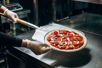 Close up shot of placing pizza to oven at pizzeria