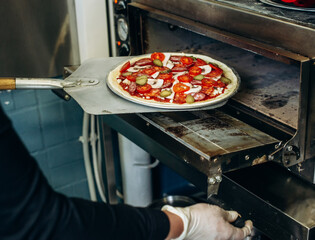 Close up shot of placing pizza to oven at pizzeria