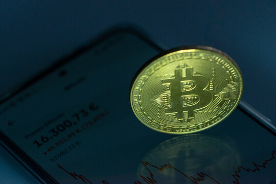 Bitcoin in moneta d'oro su smartphone che mostra il prezzo attuale del mercato azionario della criptovaluta bitcoin - concetto emblema di blockchain