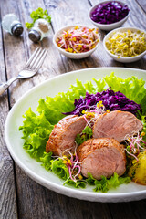 Fried pork loin with boiled potatoes and vegetables on wooden table
