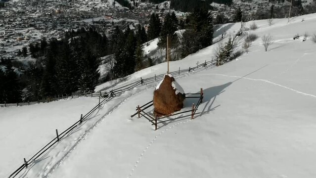 4k drone around flight above alone snow covered haystack- winter in the mountains at day. authentic slavic landscape. haystacks around. Ukraine