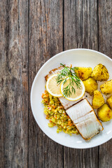 Fish dish - fried halibut with French fries and lemon on wooden table
