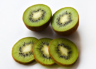 Naklejka na ściany i meble Chopped fruit of green juicy kiwi on a white background. Delicious kiwi slices close-up.