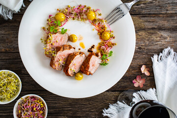Fried pork loin with fresh vegetables on wooden table
