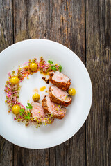 Fried pork loin with fresh vegetables on wooden table
