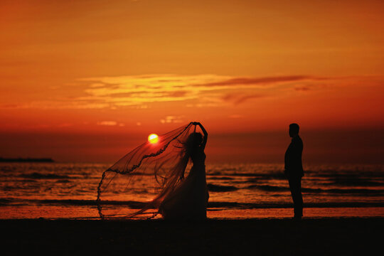 silhouette of a wedding couple on the beach at orange sunset