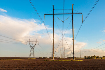 outside the city on nature pylons with high-voltage electricity against the blue sky