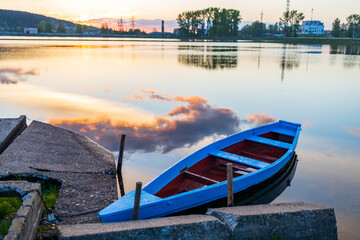 blue wooden boat on the lake near the old stone pier