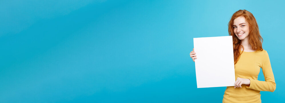 Close Up Portrait Young Beautiful Attractive Ginger Red Hair Girl Smiling Showing Blank Sign. Blue Pastel Background. Copy Space.