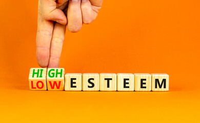High or low esteem symbol. Concept words High esteem and Low esteem on wooden cubes. Businessman hand. Beautiful orange table orange background. Business high or low esteem concept. Copy space.