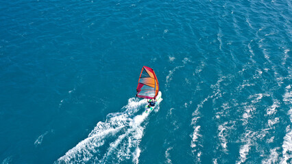 Aerial frone view photo of fit man practising wind surfing in Mediterranean bay with crystal clear...