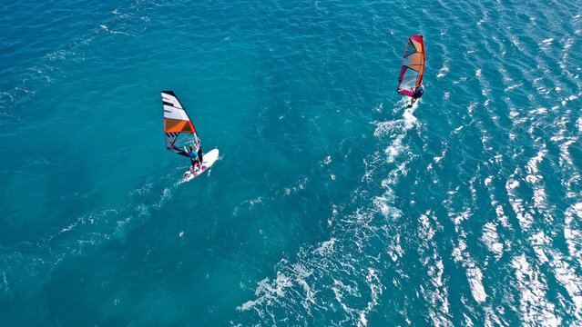 Aerial frone view photo of fit man practising wind surfing in Mediterranean bay with crystal clear deep blue sea
