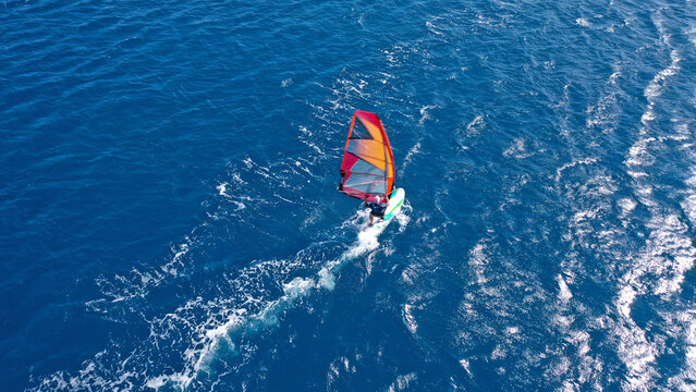Aerial frone view photo of fit man practising wind surfing in Mediterranean bay with crystal clear deep blue sea