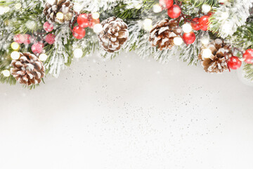 Christmas snowy fir tree branches, pine cone and bokeh garland on white background. Xmas greeting card. Space for text.