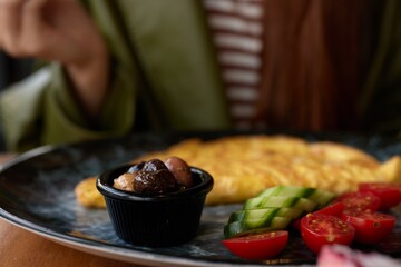 Woman in cafe having breakfast omelet with vegetables close-up of fork with food