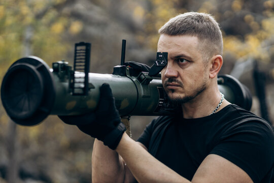 Guy and girl in military with bazooka and machine guns pose for camera