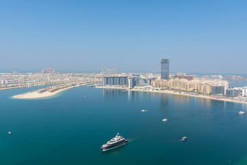 Top view from a part of the palm tree in Dubai with sea, skyscrapers and blue sea with different ships