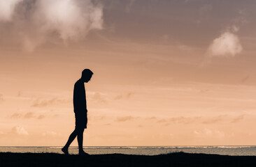 Young thoughtful male silhouette walking alone outdoors thinking 