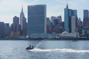 Long Island City, New York: A young couple riding a jet ski in the East River with the United...