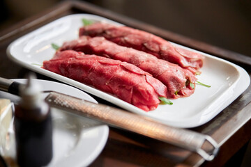 veal carpaccio in a white plate close-up on a wooden table. beef carpaccio. Plate with tasty veal carpaccio on light background.