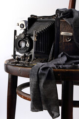 Retro photo camera, scarf and chair on a white background