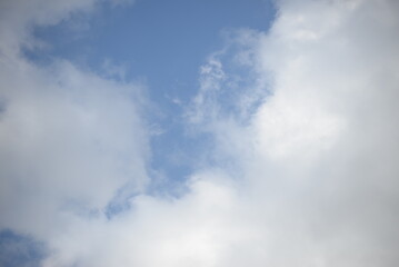 rays of the sun through cirrus clouds against a blue sky, white rainy clouds against a blue sky illuminated by the rays of the sun