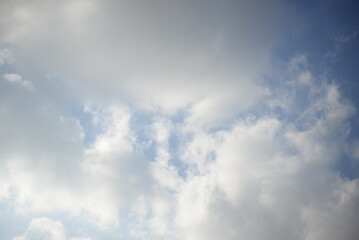 Fototapeta premium rays of the sun through cirrus clouds against a blue sky, white rainy clouds against a blue sky illuminated by the rays of the sun