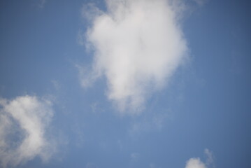 rays of the sun through cirrus clouds against a blue sky, white rainy clouds against a blue sky illuminated by the rays of the sun