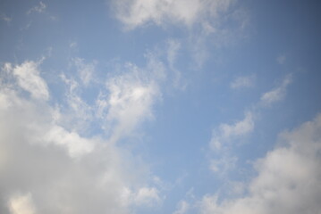 ays of the sun through cirrus clouds against a blue sky, white rainy clouds against a blue sky illuminated by the rays of the sun	
