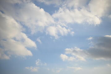 rays of the sun through cirrus clouds against a blue sky, white rainy clouds against a blue sky illuminated by the rays of the sun