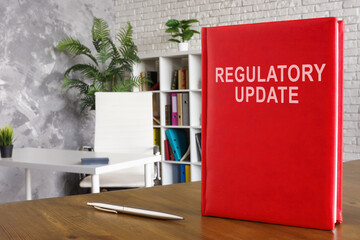 Regulatory update book on the wooden surface.