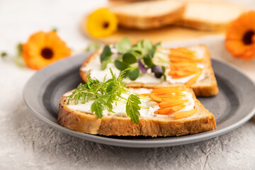 White bread sandwiches with cream cheese, calendula and microgreen on gray. side view, selective focus.