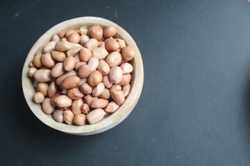 raw peanuts in wooden bowl and black background