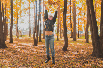Happy child throwing the fallen leaves up playing in the autumn park.
